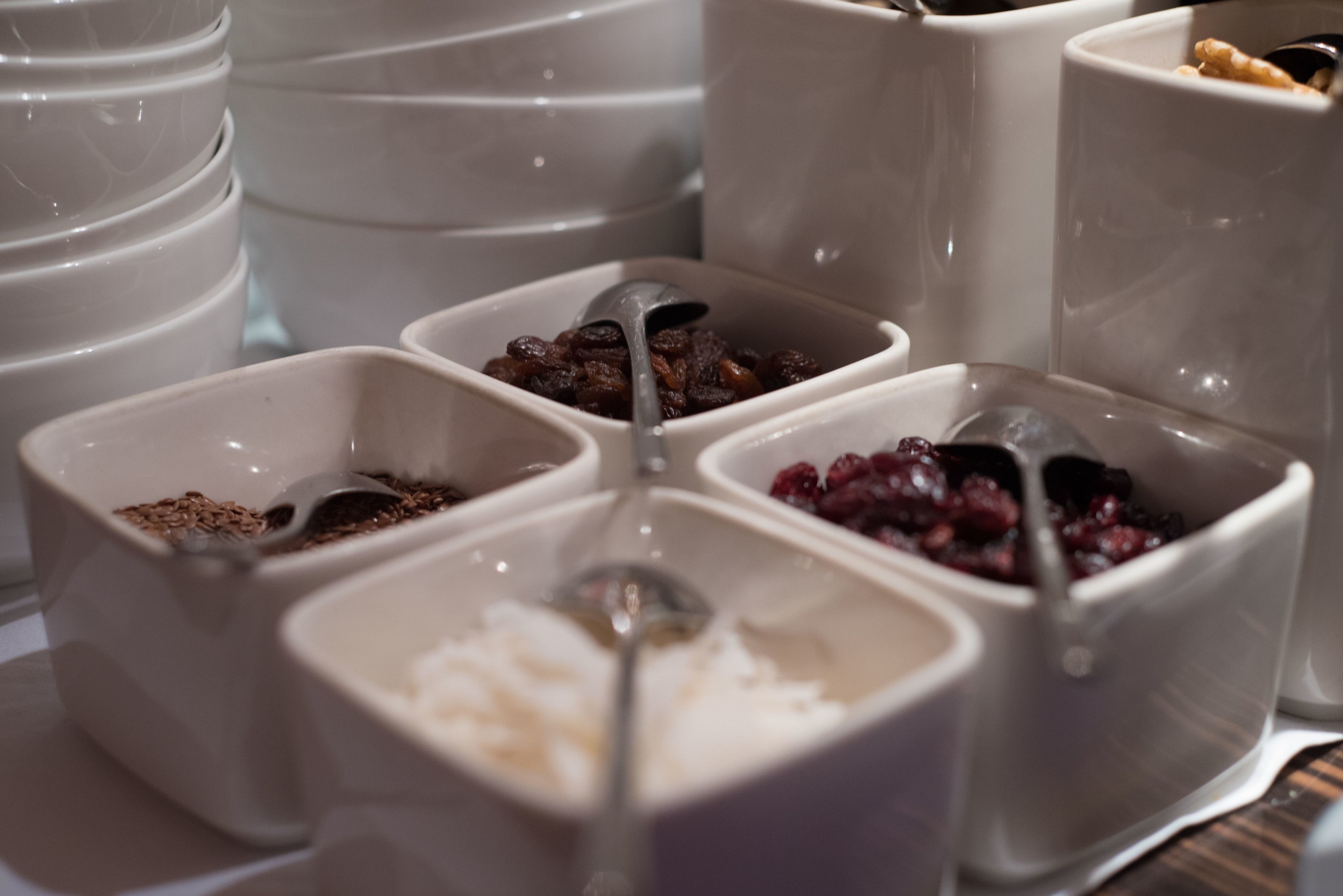 Variedad de alimentos en recipientes pequeños, como cereales, frutas secas y nueces.