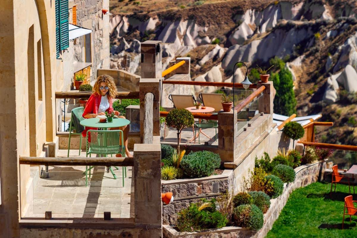 Una terraza con mobiliario exterior, muros de piedra y vistas a un paisaje montañoso.