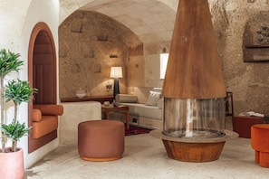 Un intérieur chaleureux avec un mur en pierre, une cheminée en bois, un canapé et une petite table.