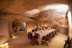 A long dining table set in a cave with candles, chairs, and a candelabra. - Hotel Taskonaklar Cappadocia - Special Class (Nevsehir)