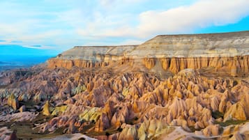 Vista panorámica de un paisaje agreste con formaciones rocosas en capas y una costa distante.
