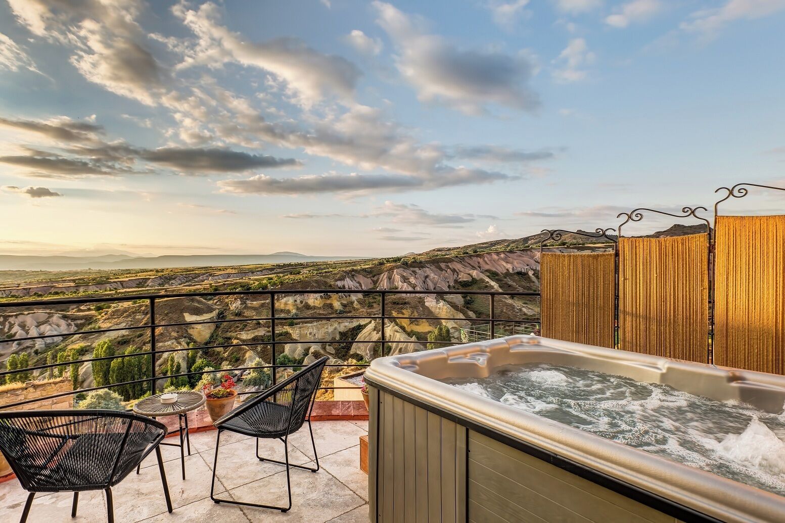 A hot tub on a balcony with a scenic view of a mountainous landscape.