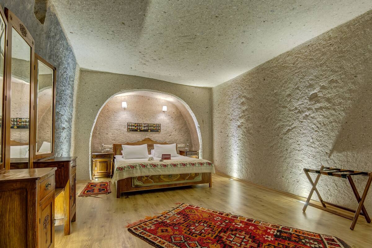 Un dormitorio con cama de madera, una mesita de noche, un aparador y un espejo.