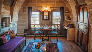 A rustic dining area with a wooden table set for two, a bench, and a view through arched windows. - Hotel Taskonaklar Cappadocia - Special Class (Nevsehir)