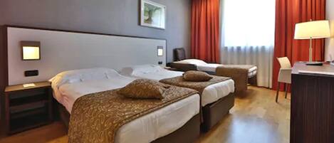 A hotel room with two beds, a desk, and a chair.