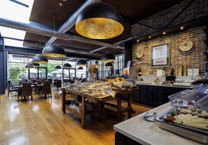 A restaurant with wooden tables, black pendant lights, and a brick wall. - Best Western Falck Village Hotel (Sesto San Giovanni)