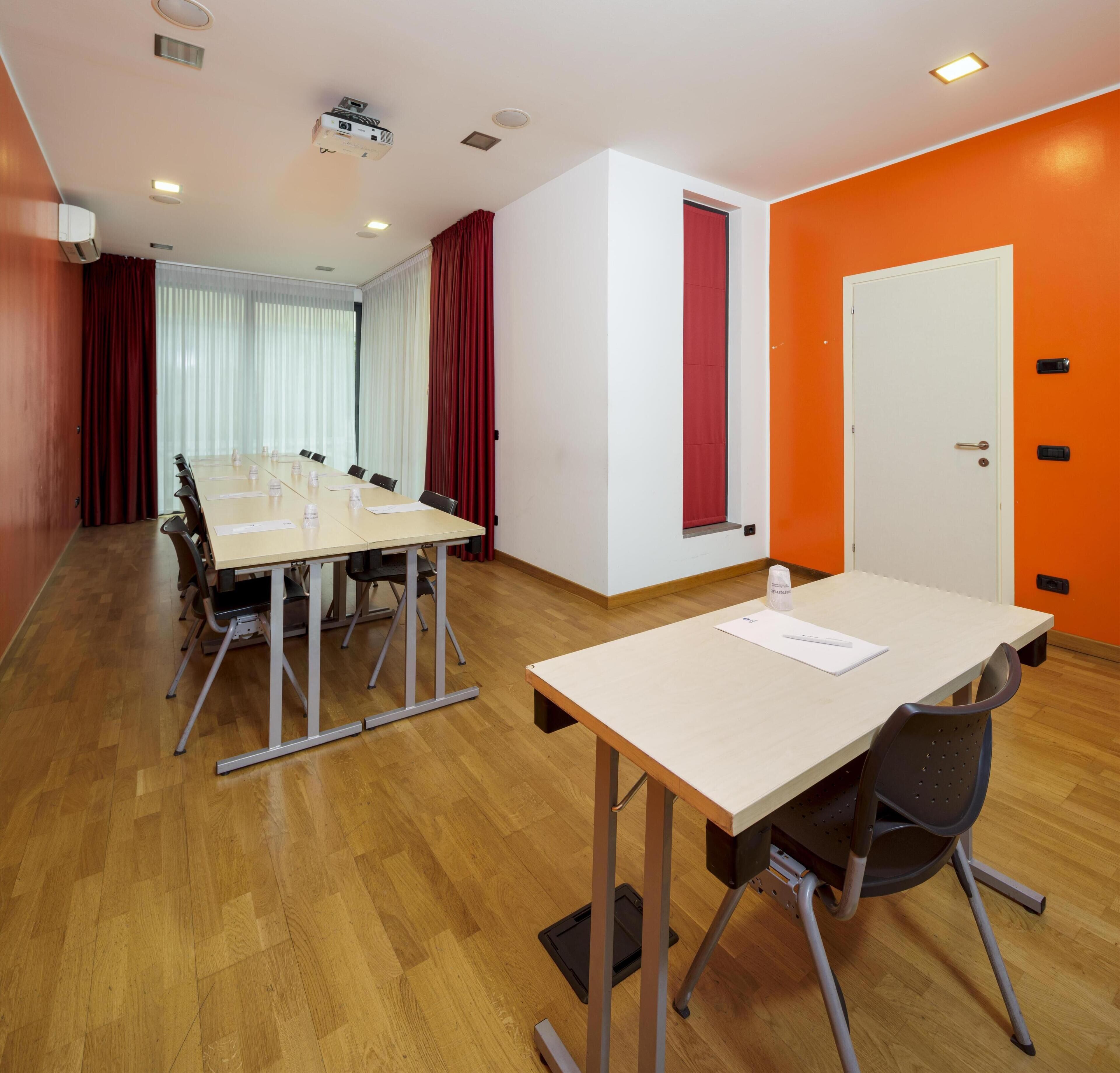 A conference room with a long table, chairs, a projector, and a whiteboard.