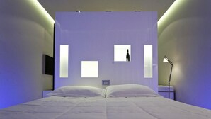 A modern bedroom with a large bed, a nightstand, a lamp, and a wall-mounted TV. - Hotel Aleramo (Asti)