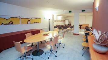 Un salón de conferencias con una larga mesa, varias sillas y una pizarra.
