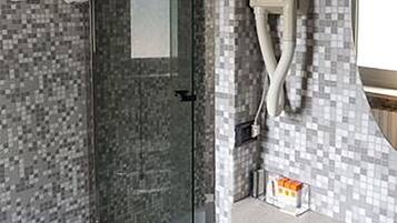 Un baño moderno con cabina de ducha de vidrio, un bidé y un lavabo con salpicadero de azulejos.