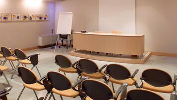 A conference room with rows of chairs facing a podium and a projection screen.