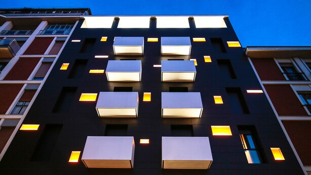 A modern building with multiple balconies and illuminated windows. - Hotel Aleramo (Asti)