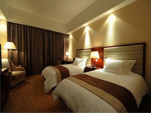 Une chambre d’hôtel avec deux lits, une chaise, un bureau et des lampes.