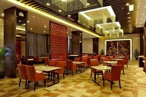 Un restaurant moderne avec un sol à carreaux, des chaises rouges et une rambarde en verre.