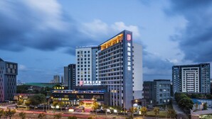 Un hotel alt amb un logotip vermell destacat, nombroses plantes i un disseny arquitectònic modern.