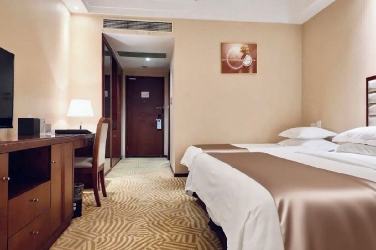 Una habitación de hotel con cama, escritorio con lámpara y televisión.