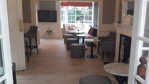 A spacious living room with a fireplace, comfortable seating, and a large TV. - Charnwood Regency (Loughborough)