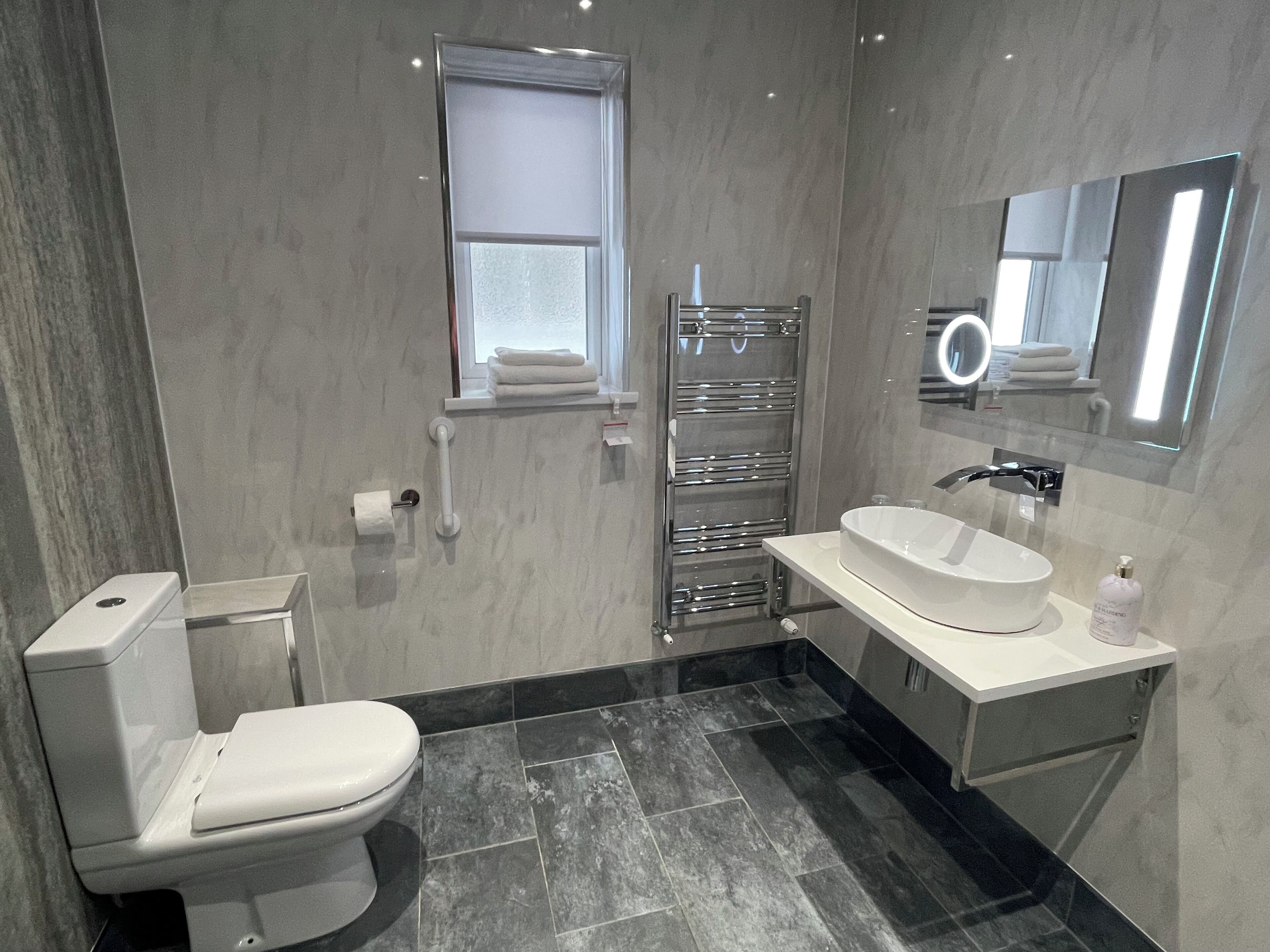 Un baño moderno con inodoro, lavabo y perchero para toallas.