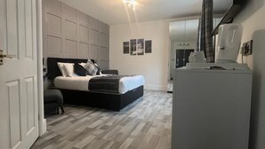 A modern bedroom with a bed, a flat-screen TV, and a built-in wardrobe. - Charnwood Regency (Loughborough)