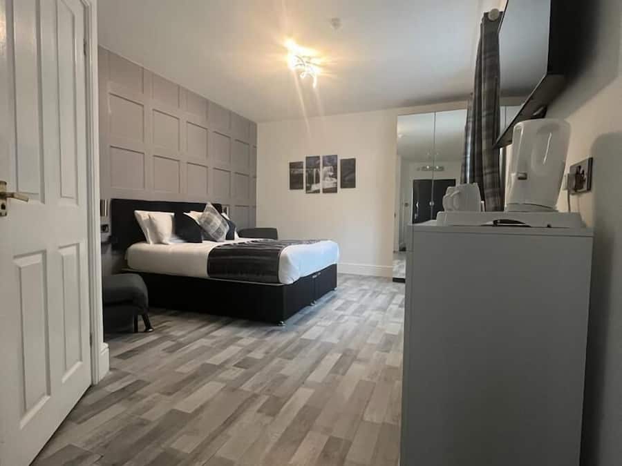 A bedroom with a bed, a wardrobe, a television, and a refrigerator.