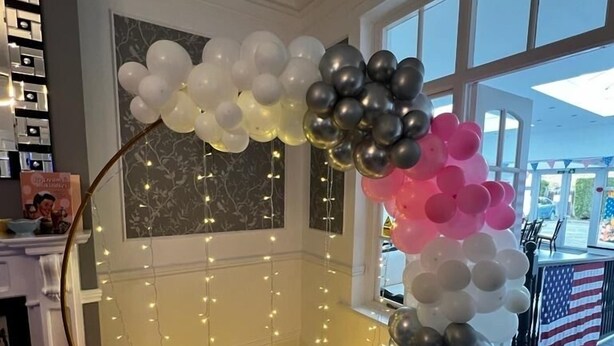 A corner decorated with a balloon arch and string lights. - Charnwood Regency (Loughborough)