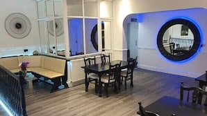 A spacious room with a high ceiling, wooden flooring, and a dining area with tables and chairs. - Charnwood Regency (Loughborough)