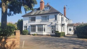 A two-story white building with multiple windows and a brick chimney. - Charnwood Regency (Loughborough)