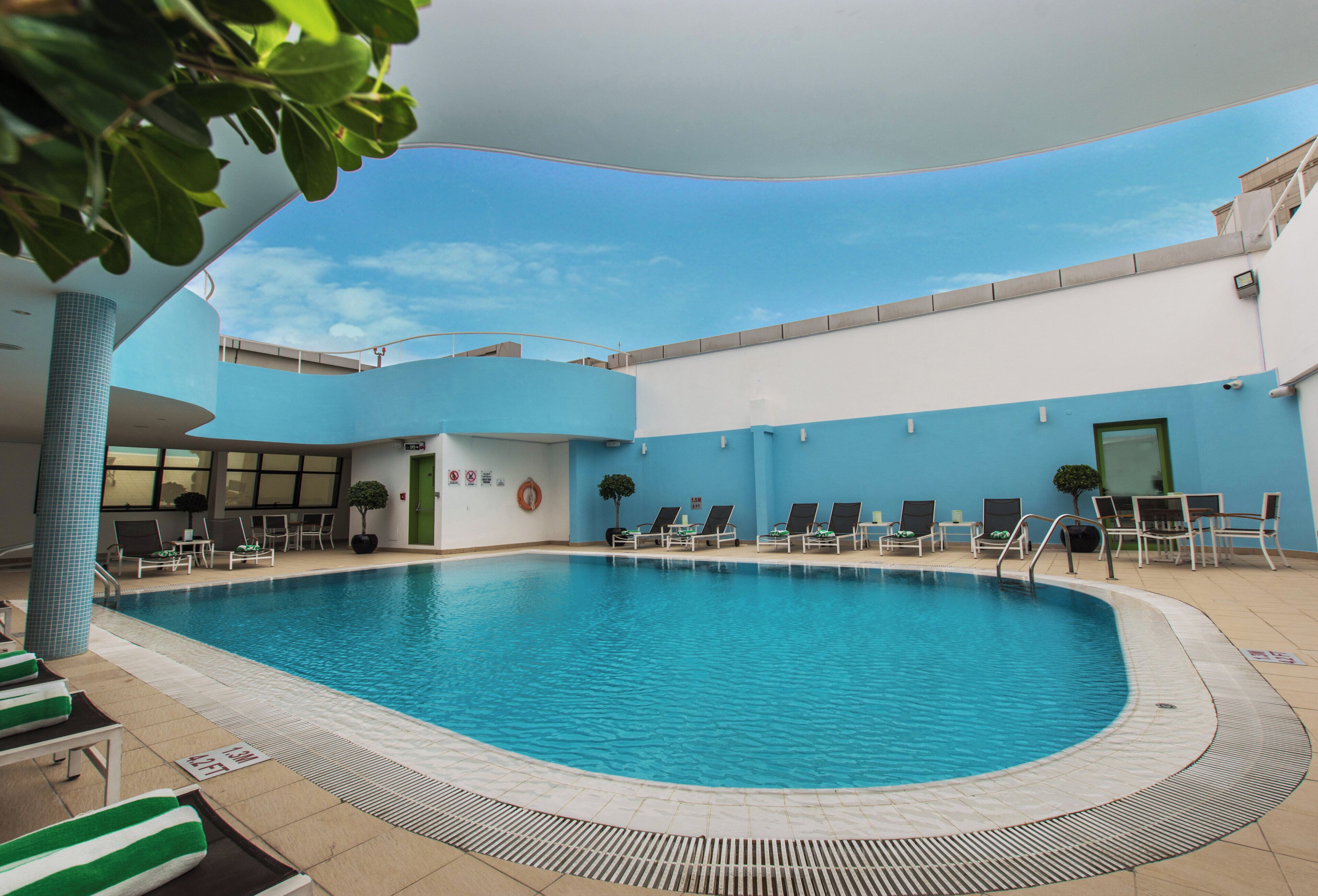 A swimming pool with lounge chairs and a tiled deck.