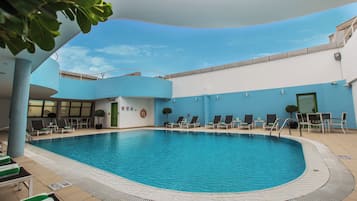 A swimming pool with lounge chairs and a tiled deck.
