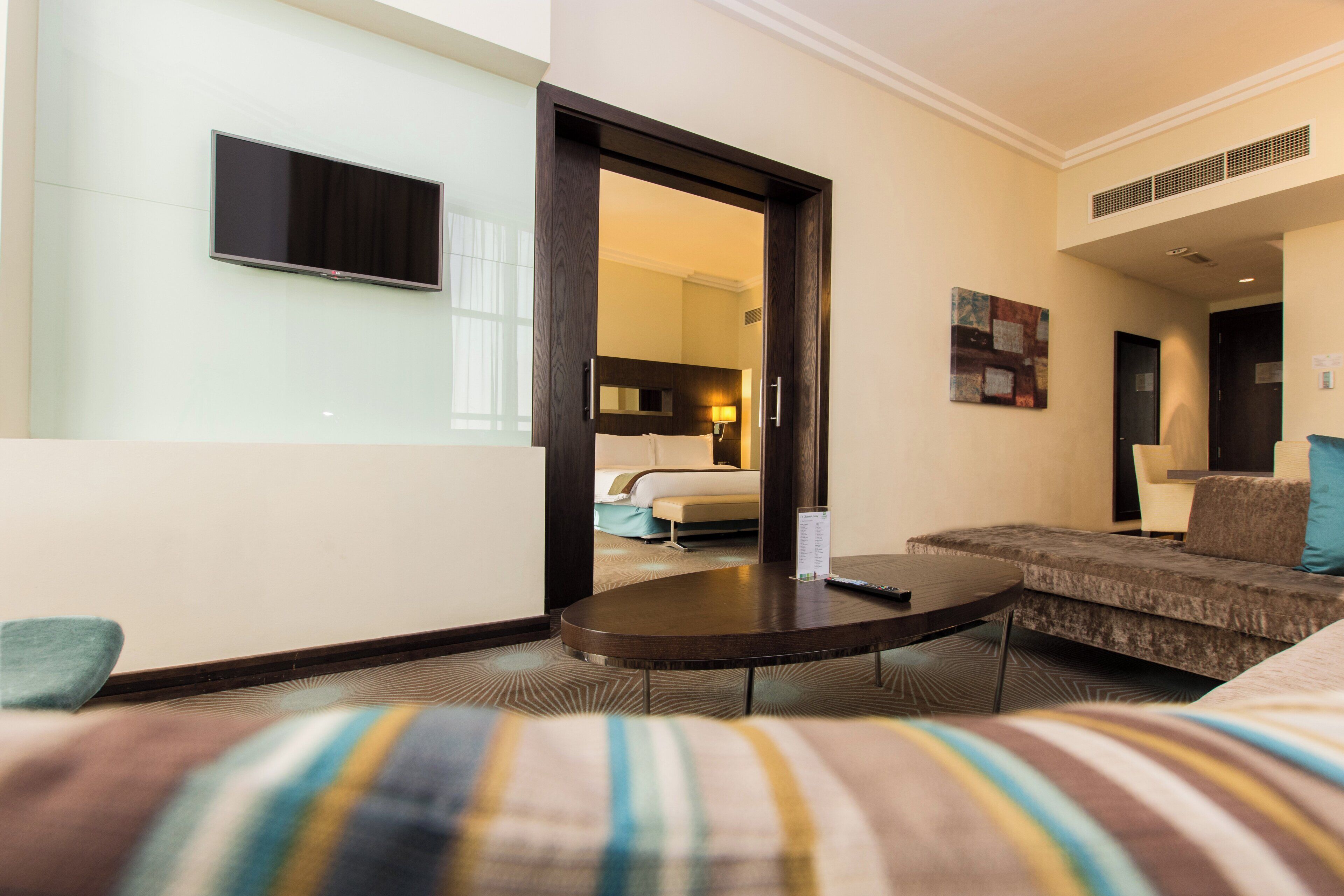 Une chambre d’hôtel avec un lit, un canapé, une télévision et une table à manger.