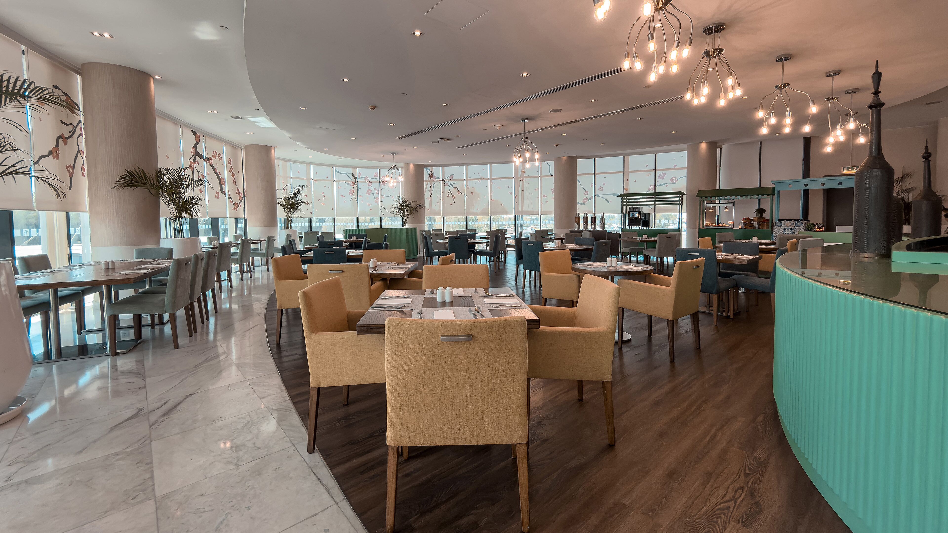 Een ruim restaurant met hoge plafonds, modern licht en een gevarieerde indeling.