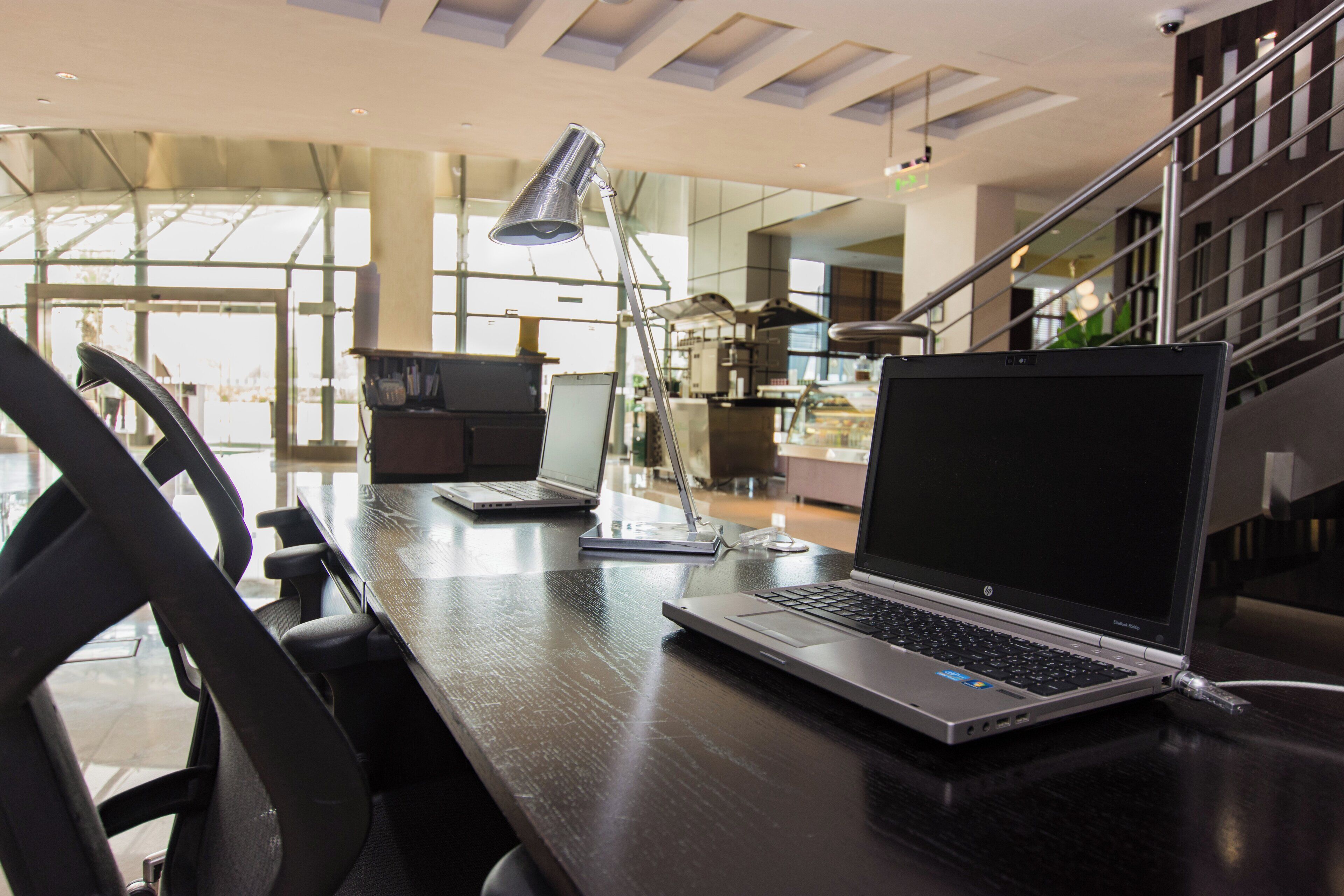 A modern office space with a laptop on a desk, a chair, and a desk lamp.
