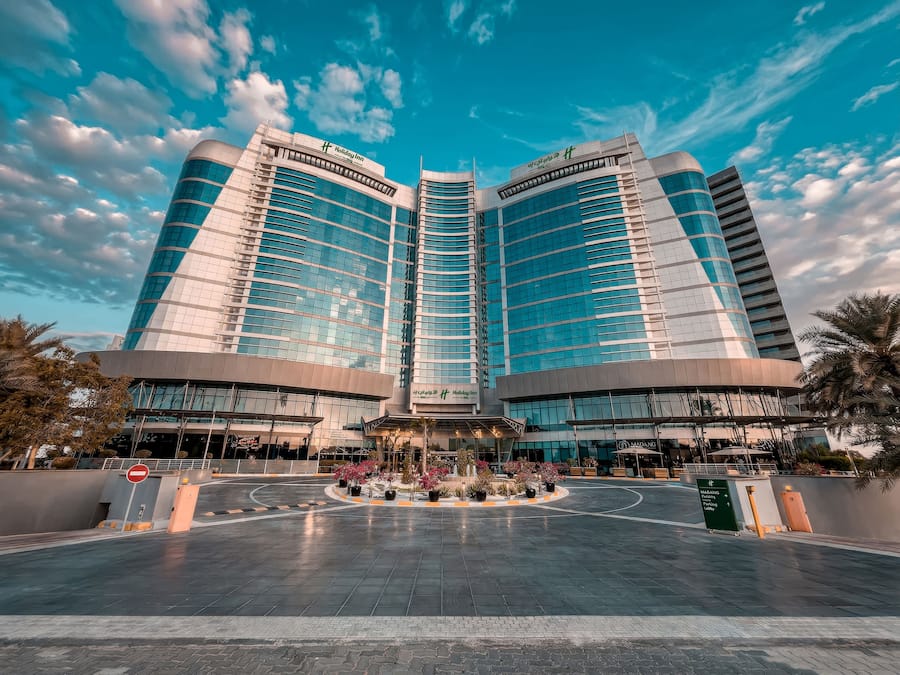 A modern hotel with a central atrium, large glass windows, and a prominent Holiday Inn sign.