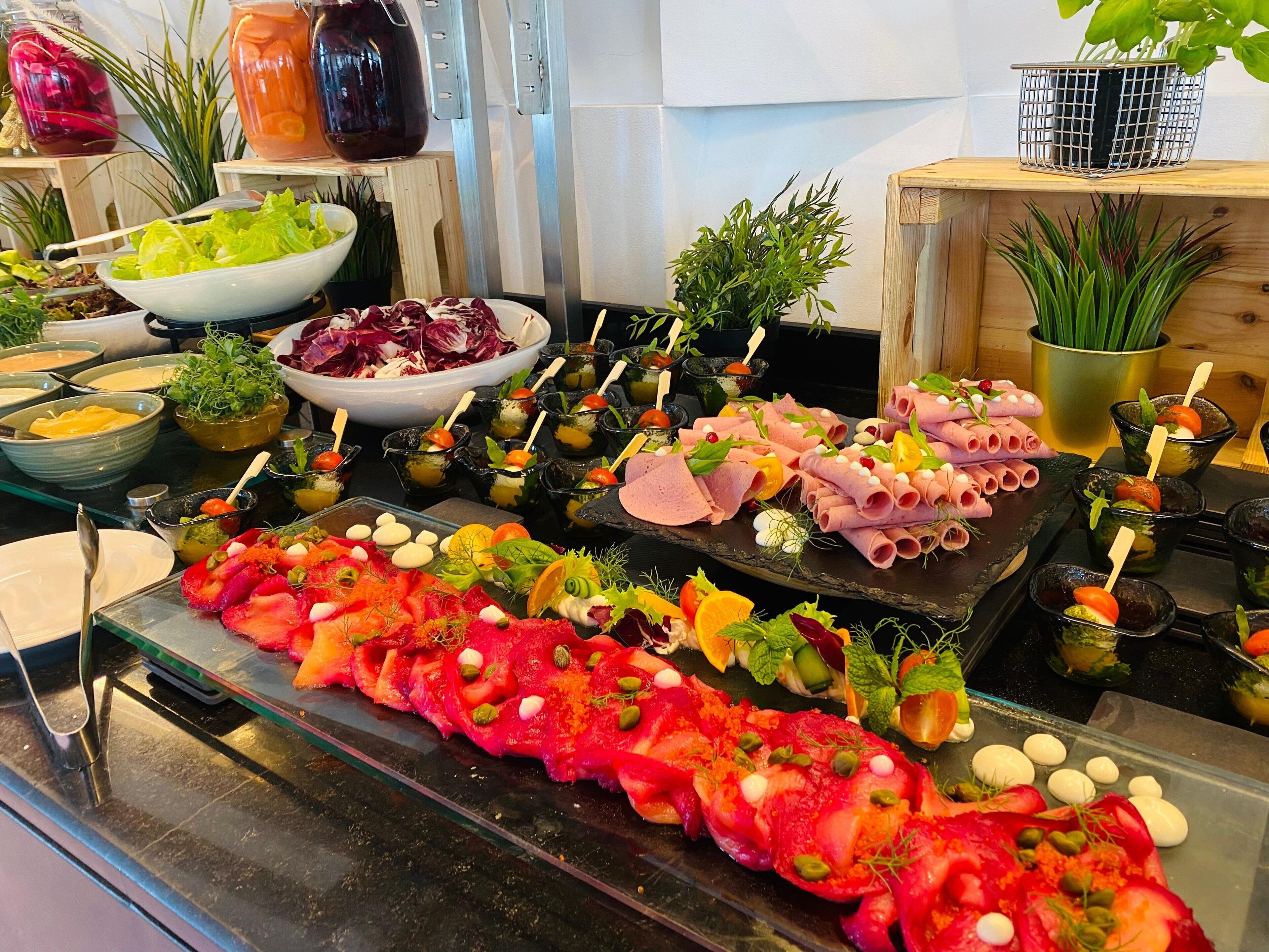 Un buffet proposant une variété de plats, notamment des viandes, des fromages et des salades.