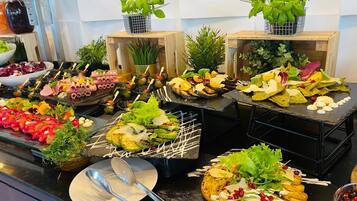 A buffet with various dishes, including salads, meats, and vegetables, arranged on black slate serving boards.