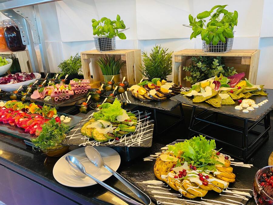 A buffet with various dishes, including salads, meats, and vegetables, arranged on black slate serving boards.