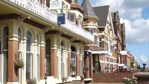 A row of Victorian-style buildings with a well-maintained lawn and flower beds. - The Palm Court Hotel (Great Yarmouth)