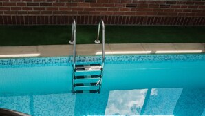 A swimming pool with a metal ladder and steps leading down to the water. - The Palm Court Hotel (Great Yarmouth)