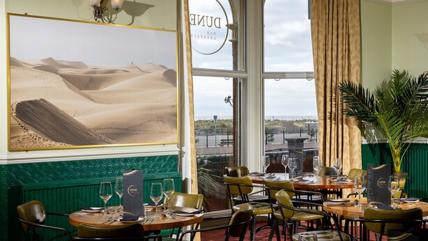 A restaurant with a desert landscape painting, a view of the city, and a green wall. - The Palm Court Hotel (Great Yarmouth)