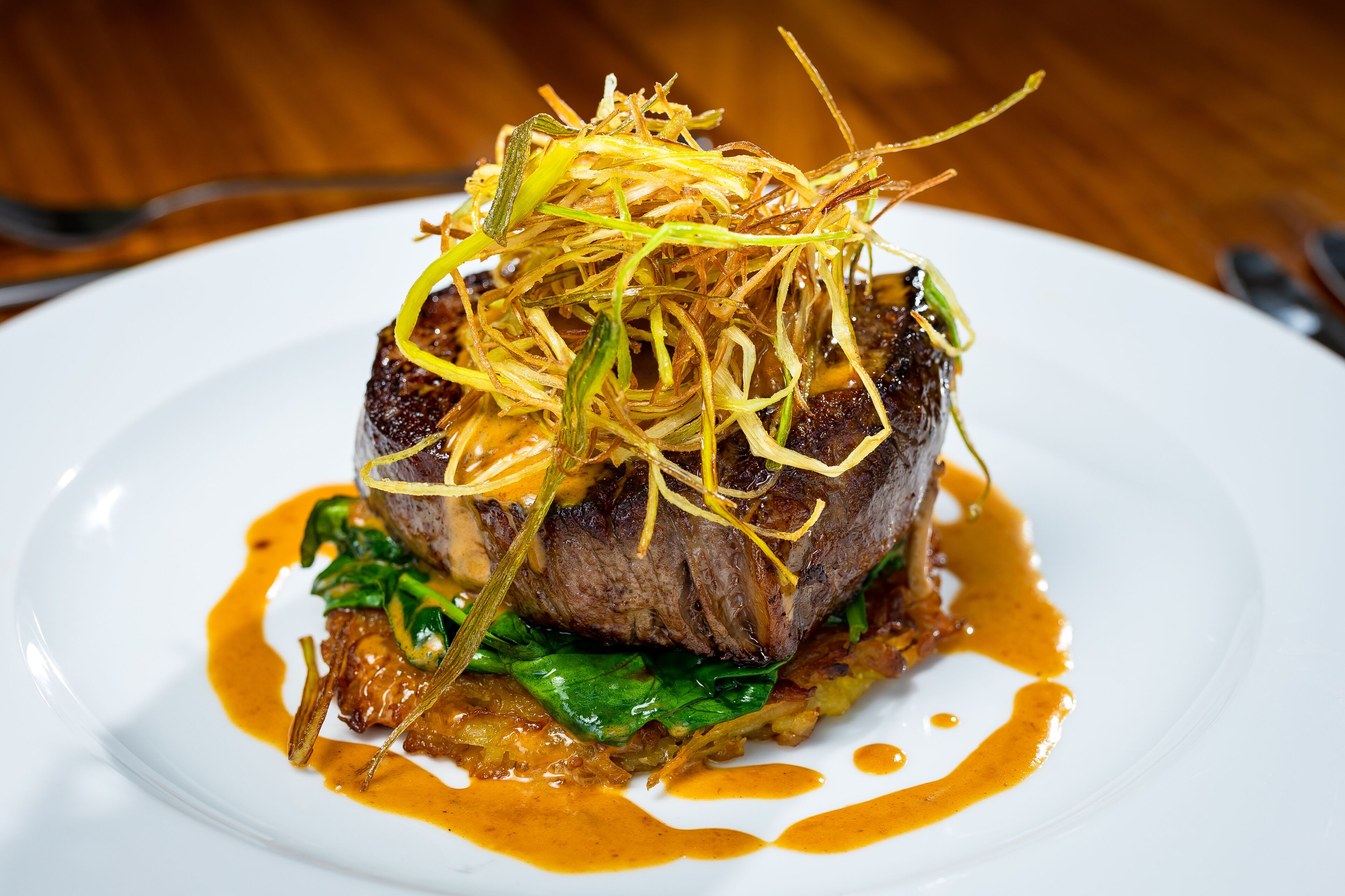 Un plato de comida con carne, vegetales verdes y salsa.