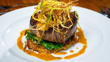 Un plato de comida con carne, vegetales verdes y salsa.
