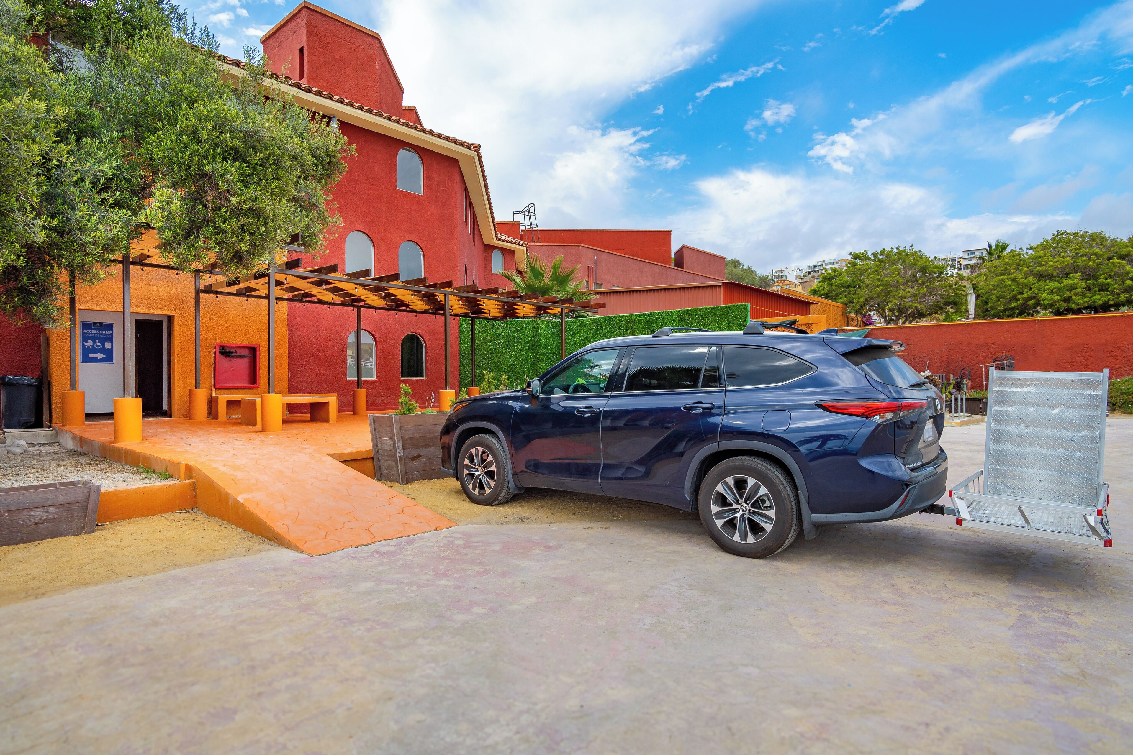 A blue SUV parked in front of a red building with a covered outdoor seating area.
