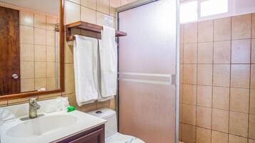 Un baño con lavabo, espejo, toallero, inodoro y cabina de ducha.