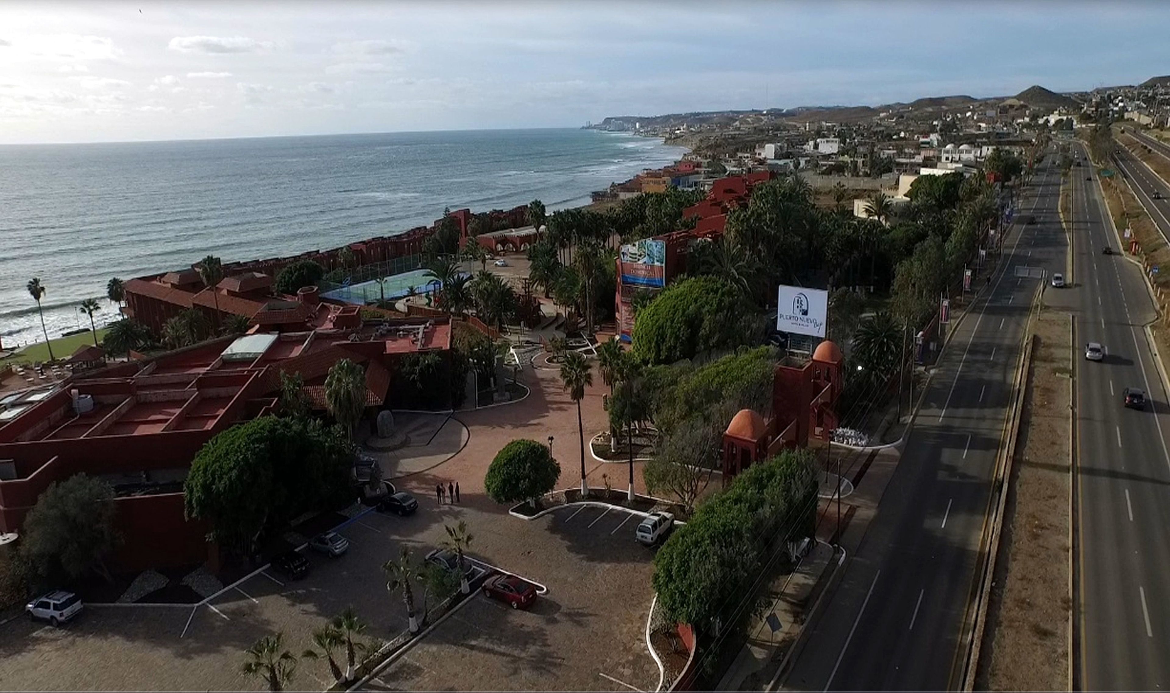 Un hotel frente al mar con estacionamiento, piscina y vistas al océano.
