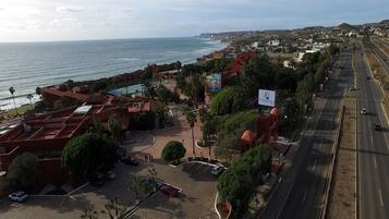Un hotel frente al mar con estacionamiento, piscina y vistas al océano.