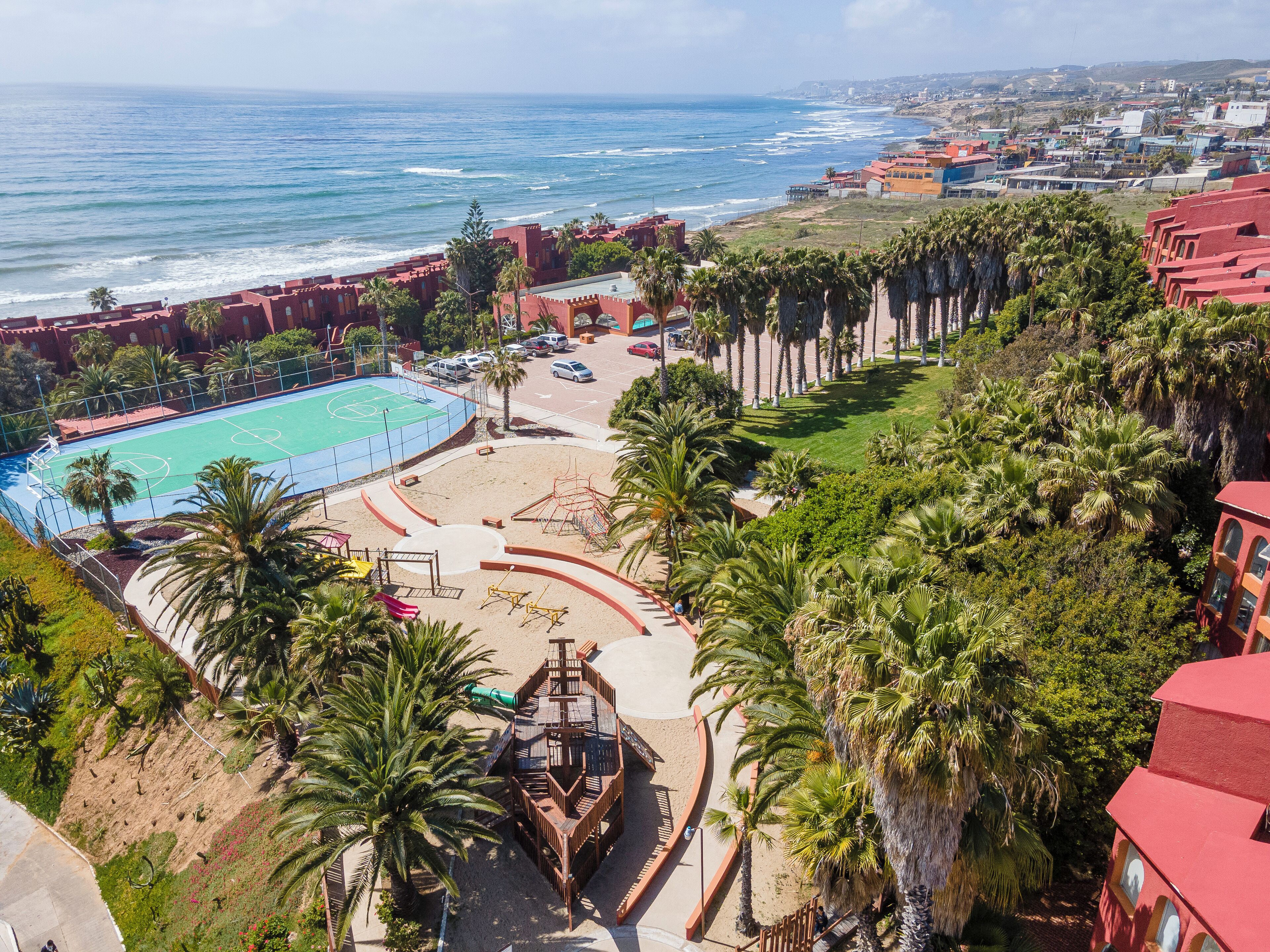 A coastal resort with a pool, beach, palm trees, and ocean views.