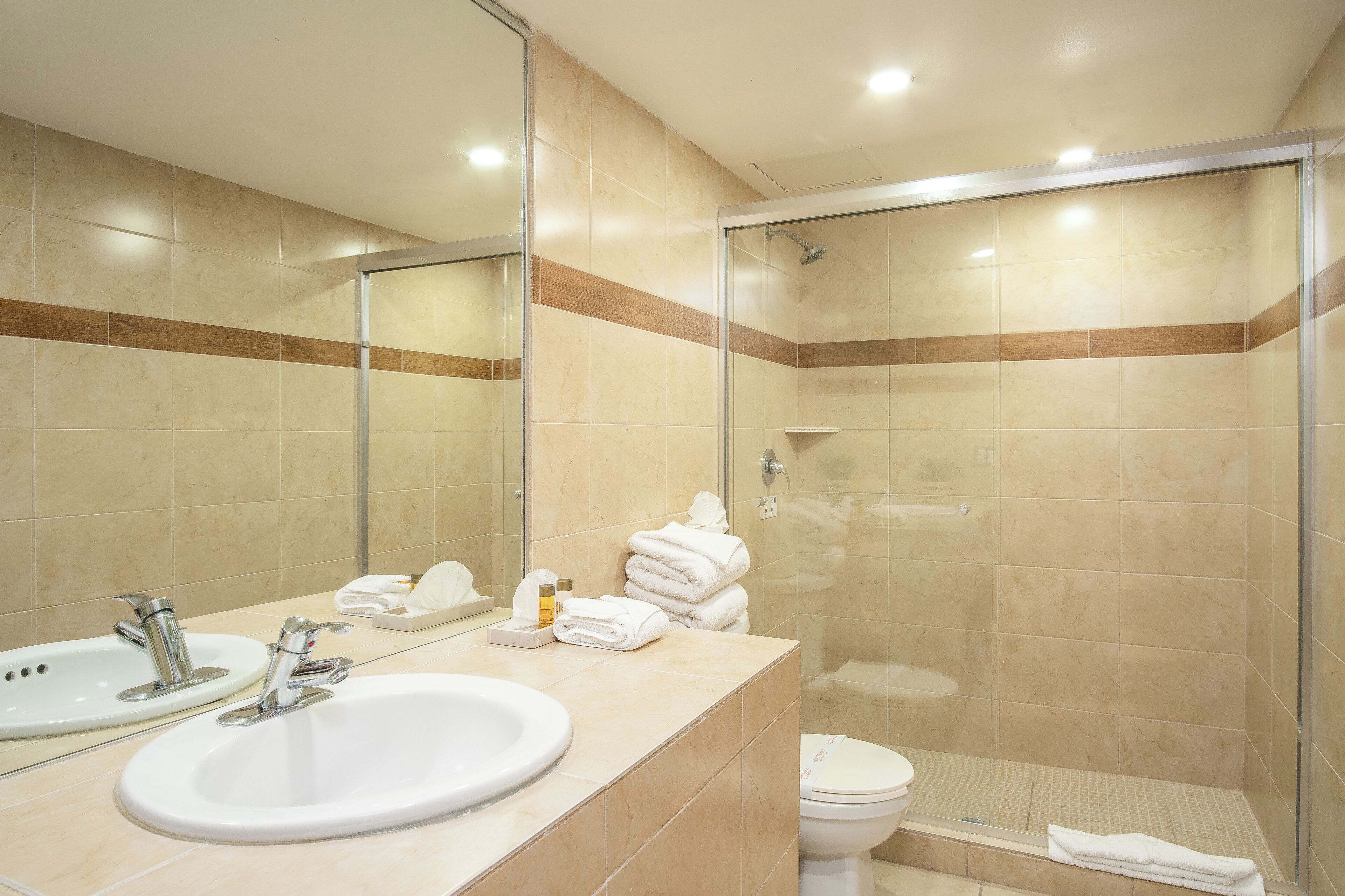 Un baño moderno con lavabo, espejo y ducha con mampara de vidrio.