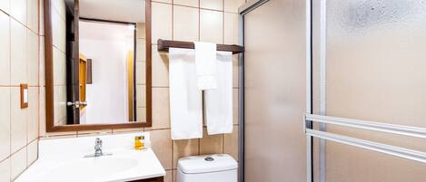 A bathroom with a white sink, a mirror, a toilet, and a shower area.