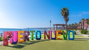 A colorful sign spelling "PERTO NUEVO" with a coastal view in the background. - Puerto Nuevo Baja Hotel & Villas (Playas de Rosarito)