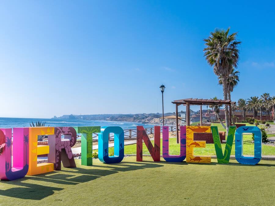 Un letrero llamativo que dice "PERTO NUEVO" con vistas al mar de fondo.